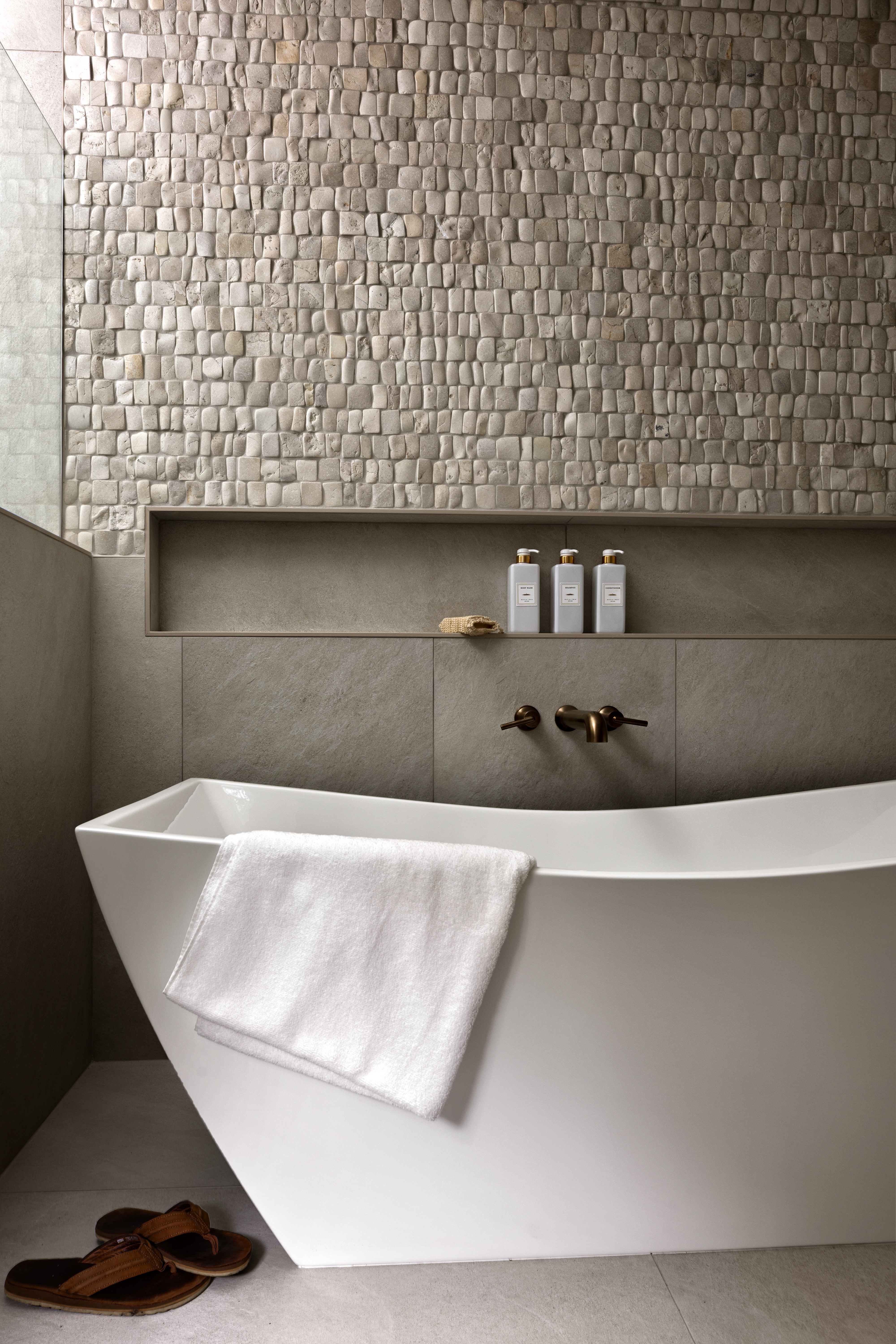 Freestanding bathtub and stone tile — bathroom detail photography